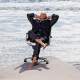 A man in a suit, embodying great management, relaxes on an office chair by the beach, with tranquil waves rolling in the background.