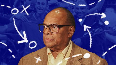 Man in glasses and a brown jacket with a serious expression; the background features a blue overlay adorned with white sports strategy symbols and a cheering crowd. It's reminiscent of a Coach Raveling masterclass, where every move is meticulously planned.