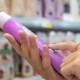 In the store aisle brimming with products, a person examines the label of a purple bottle, curious about the latest scienceploitation claims that promise groundbreaking benefits.