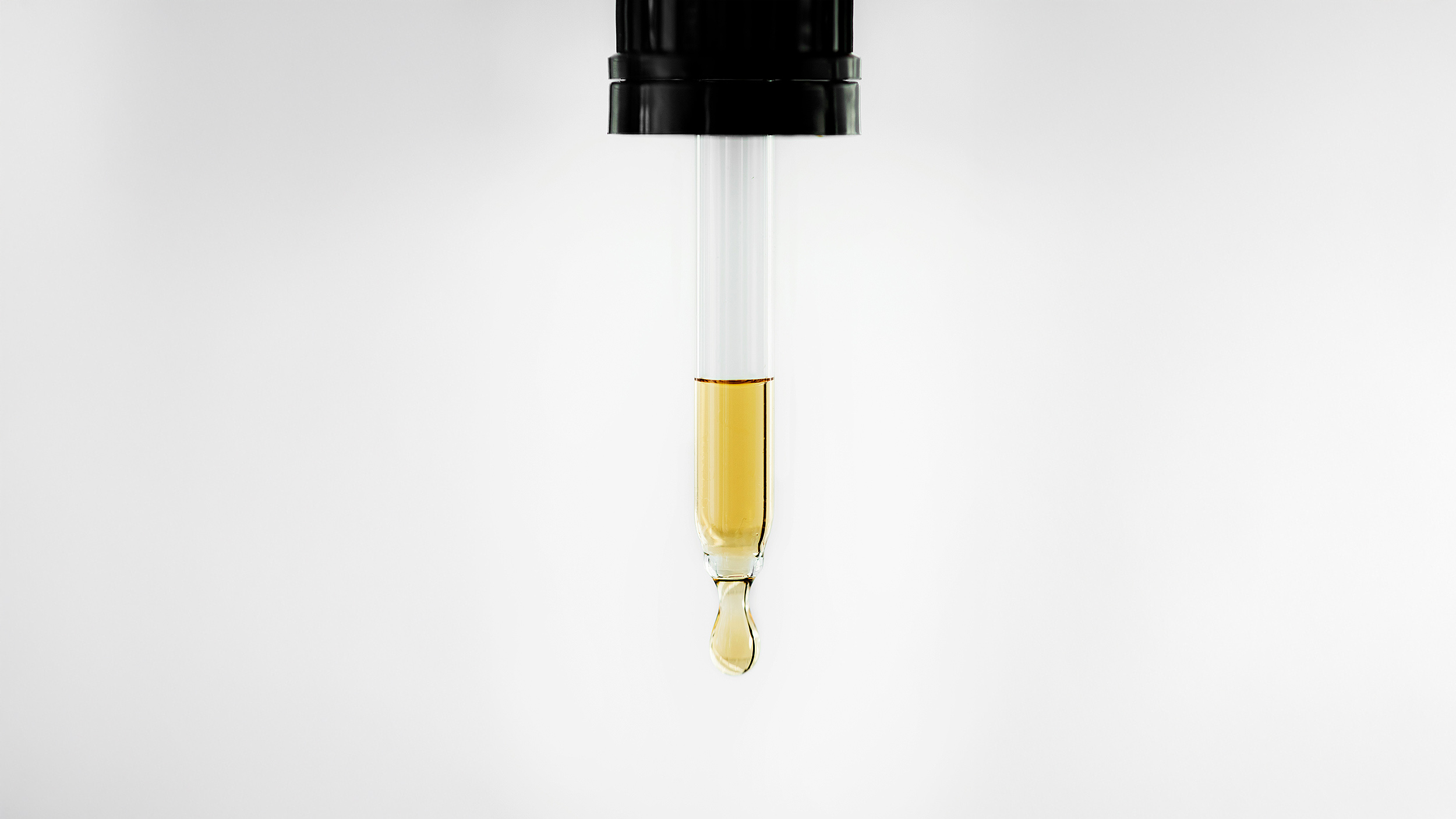 Close-up of a dropper releasing a drop of yellow liquid, showcasing the foundation of chemistry against a pristine white background.